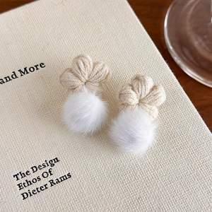 Macro d'une paire de boucles d'oreilles fleurs tricotées avec pompons blancs doux