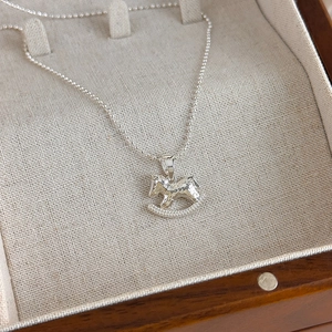 Detail of silver rocking horse pendant with hammered texture and pavé set crystals