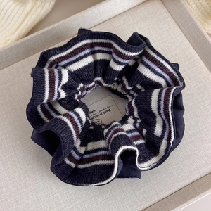 Detail showing soft navy blue striped knit scrunchie with French retro pattern