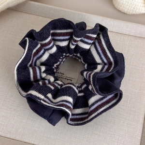 Detail view of navy blue striped knit scrunchie with retro academic style texture