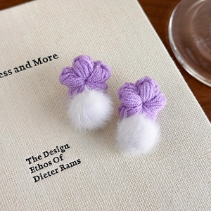 Détail de boucles d'oreilles fleurs au crochet violet avec pompon blanc en fausse fourrure