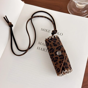 Close-up of leopard print lipstick bag necklace with silver snap button on vintage book