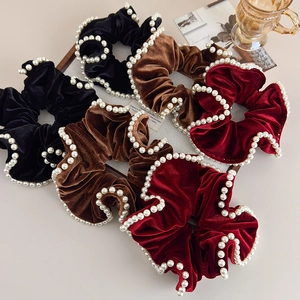 Detail of velvet scrunchies with faux pearl trim in black, brown, and burgundy colors