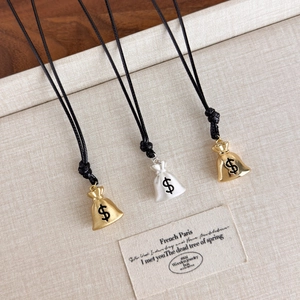 Detailed close-up of lucky money bag pendants with dollar sign on woven cord necklace
