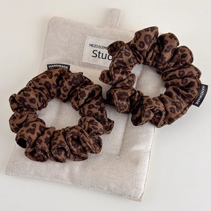 Leopard print faux suede scrunchies with handmade label on beige fabric background
