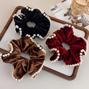 Detailed close-up of velvet hair scrunchies with white pearl edges in three colors
