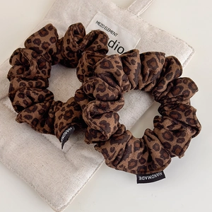 Close-up of leopard print suede scrunchies with a handmade label on a soft background