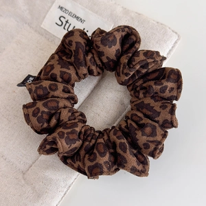 Detailed view of leopard print velvet hair scrunchie with soft suede texture and woven label