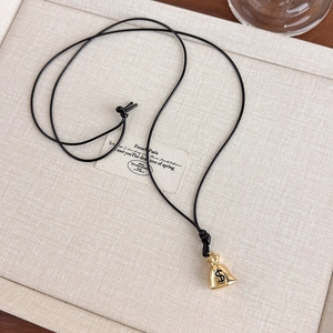 Detailed close-up of a golden money bag pendant with a dollar sign on a beige display tray