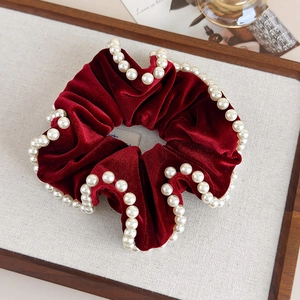 Detailed view of burgundy velvet scrunchie with pearls and pleated vintage texture