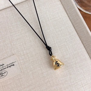 Detailed close-up of a golden money bag pendant with dollar sign on a jewelry tray