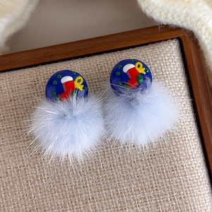 Makroaufnahme blauer Plüsch-Pompon-Weihnachtsohrringe auf einem rustikalen Holzsockel