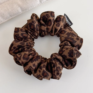 Detailed view of leopard print faux suede hair scrunchie with handmade woven label