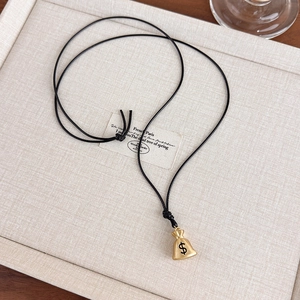 Detail of money bag pendant with dollar sign on adjustable black braided cord necklace