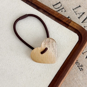 Détail d'un élastique à cheveux avec pendentif en forme de cœur doré au métal brossé chic