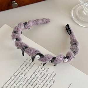 Dettaglio di un cerchietto in maglia viola con perle, strass e fermagli per capelli inclusi