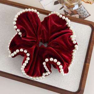 Detailed view of burgundy velvet scrunchie with elegant white faux pearl edge trim