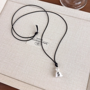 Detailed view of silver money bag pendant with black dollar sign on wax cord necklace