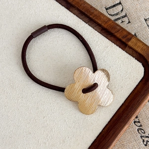 Vue macro d'un pendentif fleur dorée brossée sur élastique à cheveux marron
