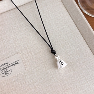 Detailed macro view of money bag pendant with dollar sign on woven black rope necklace