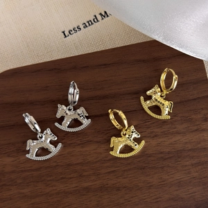 Elegant gold and silver rocking horse earrings with hammered texture on wooden board