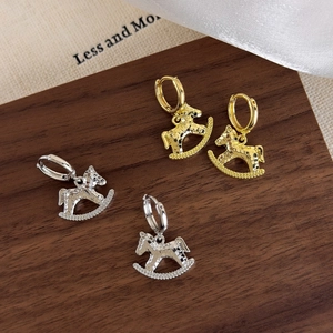 Detailed view of textured gold and silver Trojan horse earrings on a wooden background