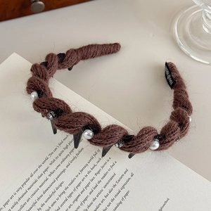 Dettaglio macro del cerchietto in maglia marrone con perle bianche e strass lucenti