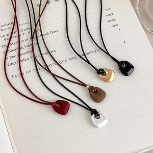 Detailed view of matte pebble pendants in five colors on an open vintage book background