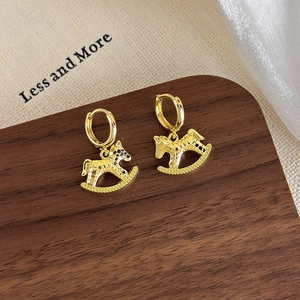 Detail view of golden rocking horse hoop earrings with a textured hammered finish