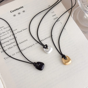 Detailed view of brushed geometric pendants in black, gold, and silver on a vintage book