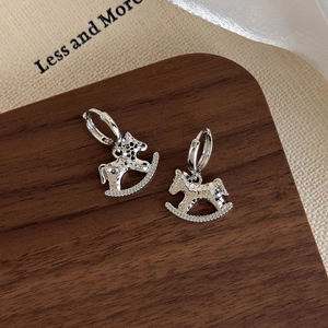Detailed close-up of silver rocking horse earrings with hammered texture and pave zircon
