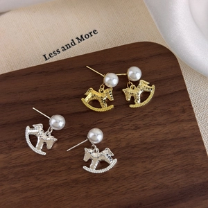 Elegant rocking horse pearl earrings in gold and silver finish with hammered metal texture
