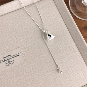 Macro shot of silver money bag pendant necklace with black dollar sign and Y-chain design