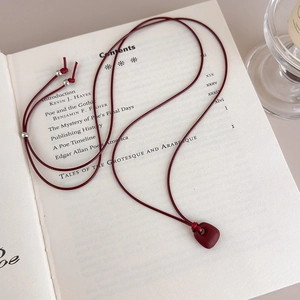 Close-up of retro dark red pendant with matte texture on vintage book background