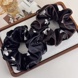 Detail of velvet scrunchies with butterfly prints in black and brown on wooden tray