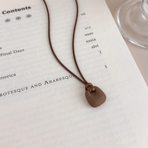 Macro shot of matte brown square pendant on an open book for a minimalist look