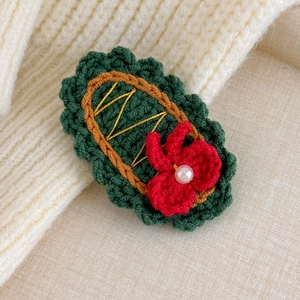 Close-up of handmade crochet Christmas hairpin with red flower and pearl detail