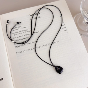 Detailed close-up of a black stone pendant necklace resting on a literary book page