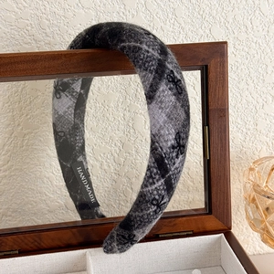 Detail of grey plaid wool headband with black bow patterns and handmade inner label