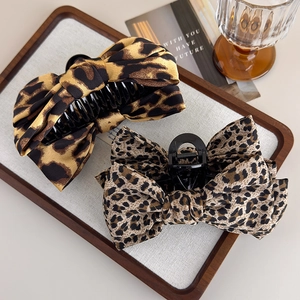 Detailed view of two leopard print bow hair claws placed on a wooden tray