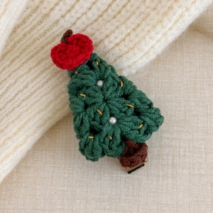 Close-up of handmade knitted Christmas tree hair clip with white pearls and gold thread detail