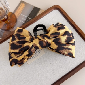 Close-up of leopard print bow hair claw clip on a rustic wooden decorative tray