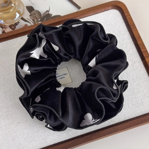 Detail of a large black velvet scrunchie with white butterfly print on a decorative tray