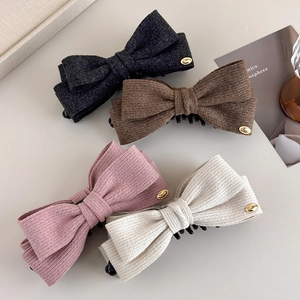 Detailed view of four wool bow hair clips with gold LOVE metal tags in elegant colors