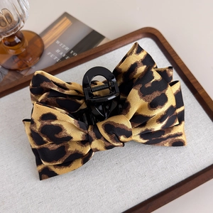 Detailed view of leopard print bow hair claw clip with satin finish and metal spring