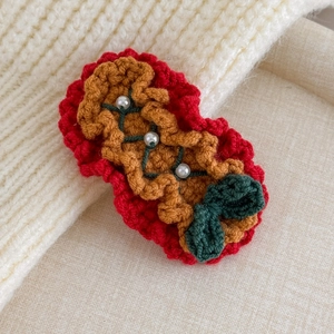Close-up of handmade knit Christmas hair clip with white pearls and green bow detail