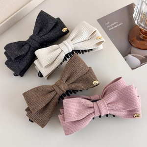 Detailed view of textured wool fabric bow hair clips with gold love metal accents