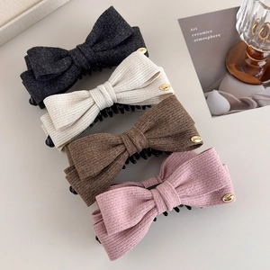 Detail view of four wool-like bow hair clips in grey, cream, brown, and pink with LOVE charms