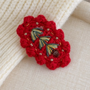 Detail showing handcrafted red crochet hairpin with festive embroidery and micro beads