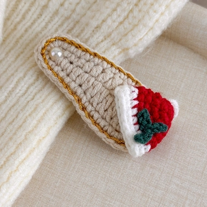 Detail of crochet Christmas hair clip with knit hat and holly on beige texture